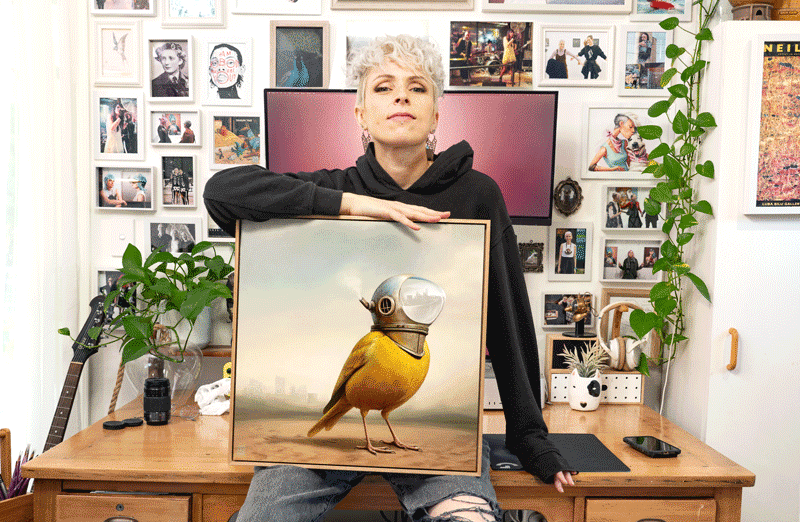 Artist Lix North with her dystopian canary oil painting 'Seer', now featured on the cover of 'Weridscapes - An Otherworldly Anthology' by Ink Alchemy Books